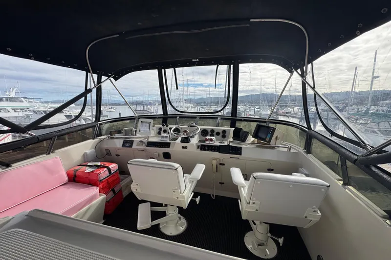 Slide: The Image of 1988 Carmague 48 CPMY yacht cockpit with dual seats, marina view, and navigation equipment. - 34