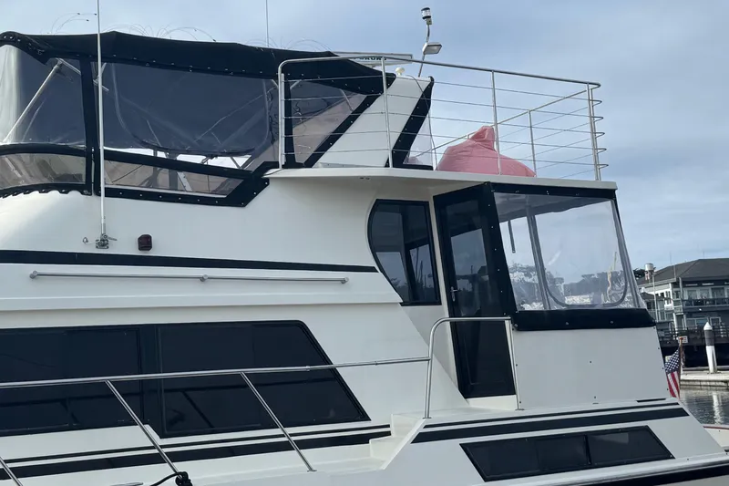 Slide: The Image of 1988 Carmague 48 CPMY yacht docked, featuring sleek design and spacious upper deck. - 39