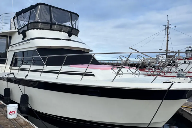 Slide: The Image of 1988 Carmague 48 CPMY yacht docked at marina, featuring sleek design and spacious deck. - 44