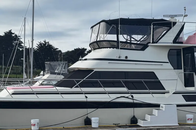 Slide: The Image of 1988 Carmague 48 CPMY yacht docked at marina, featuring sleek design and spacious upper deck. - 45
