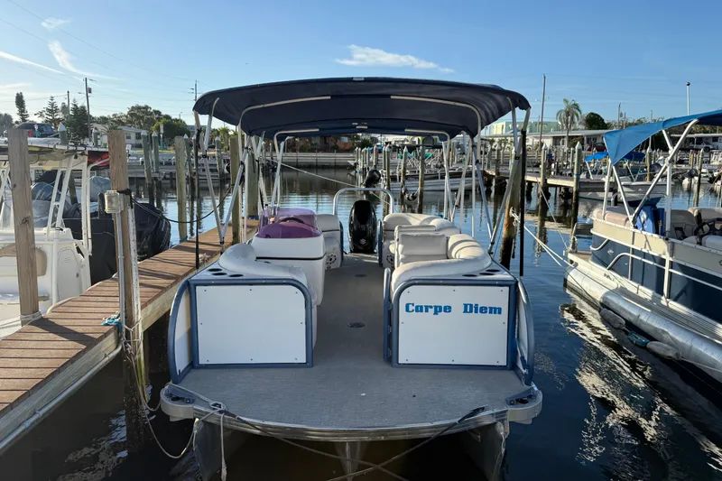 Slide: The Image of Aloha Pontoon Tropical Series 23, 2021 model, docked at a marina with "Carpe Diem" sign. - 1