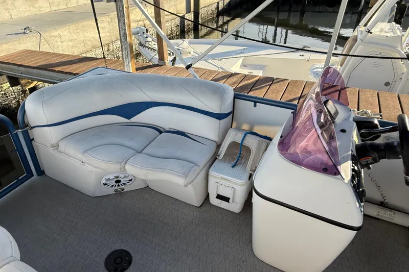 Slide: The Image of 2021 Aloha Pontoon Tropical Series 23 interior with seating and console, docked by the water. - 17