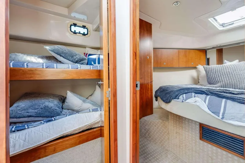 Slide: The Image of 2007 Riviera yacht interior with cozy bunk beds and a double bed, featuring wooden accents. - 18