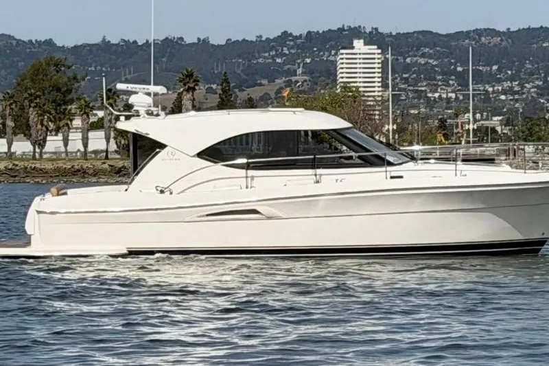 Slide: The Image of 2007 Riviera 3600 Sport Yacht cruising on a scenic waterway with cityscape backdrop. - 29