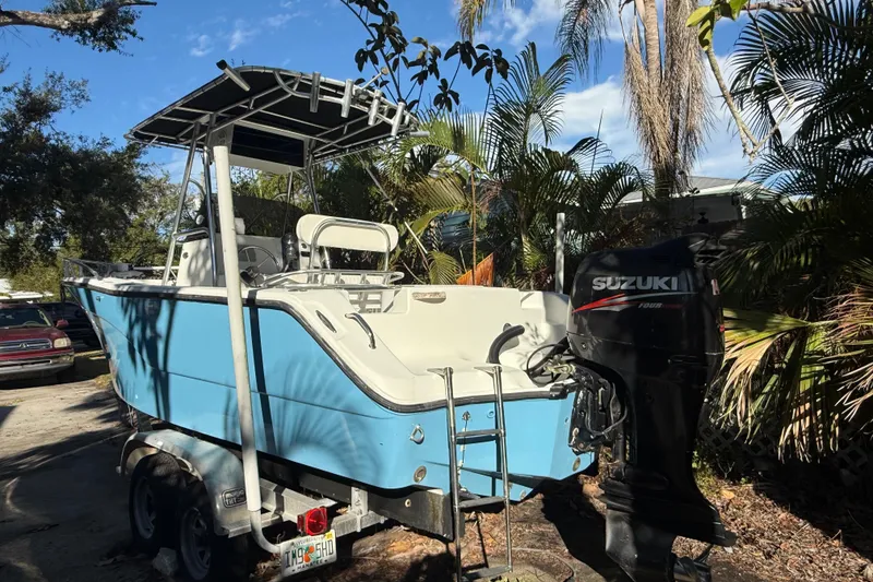Slide: The Image of Blue 2002 Fishmaster 212 Travis Edition boat with Suzuki outboard motor, parked outdoors. - 1
