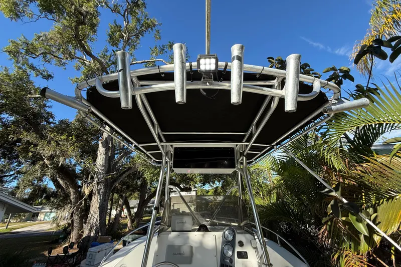 Slide: The Image of 2002 Fishmaster 212 Travis Edition boat with T-top and rod holders, surrounded by trees. - 17