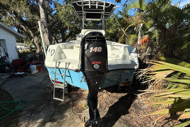 Slide: The Image of 2002 Fishmaster 212 Travis Edition boat with 140 HP outboard motor in a garden setting. - 2