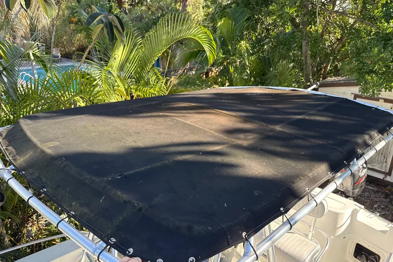 Slide: The Image of 2002 Fishmaster 212 Travis Edition boat with black canopy, surrounded by lush greenery. - 34