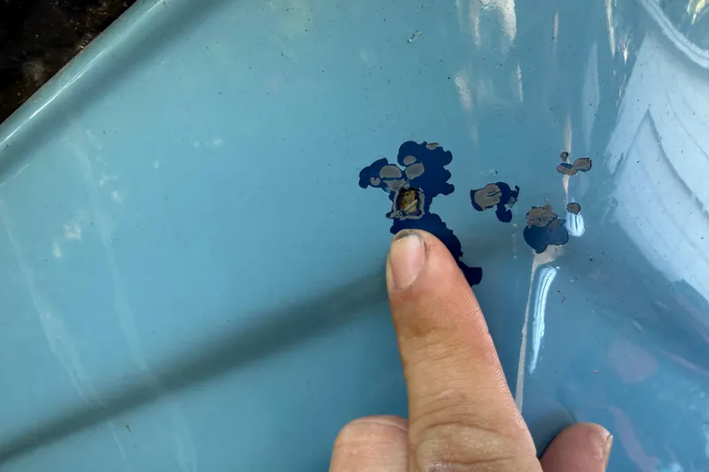 Slide: The Image of Finger pointing at chipped paint on 2002 Fishmaster 212 Travis Edition boat hull. - 38