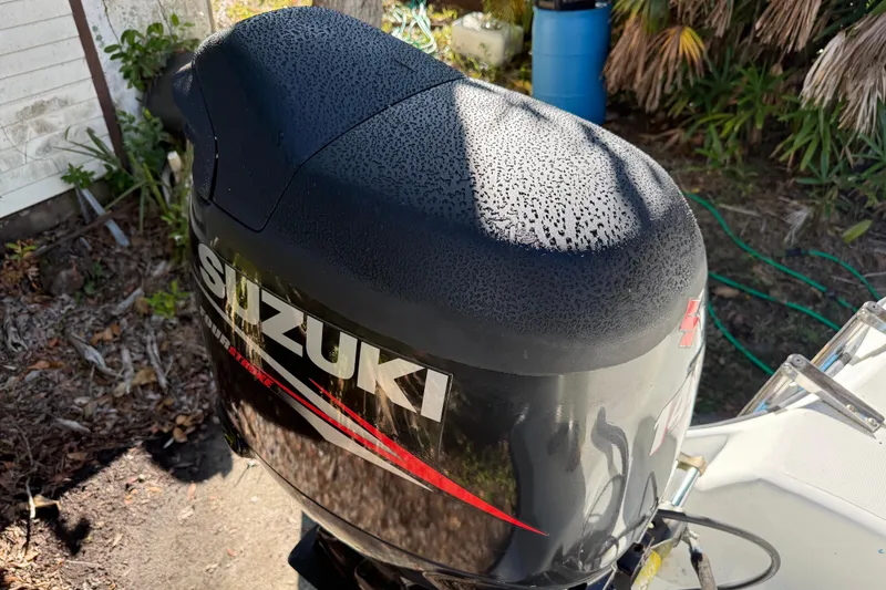 Slide: The Image of Suzuki outboard motor on 2002 Fishmaster 212 Travis Edition boat, in a garden setting. - 9