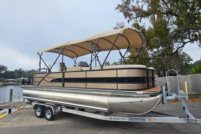 Slide: The Image of 2026 Bentley Pontoons Legacy 243 Cruise on trailer, beige canopy, parked near water. - 7