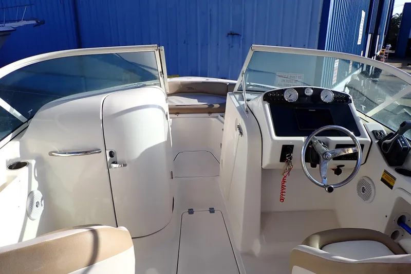Slide: The Image of 2015 Pioneer 222 Venture boat interior with steering wheel and dashboard, docked near blue building. - 6