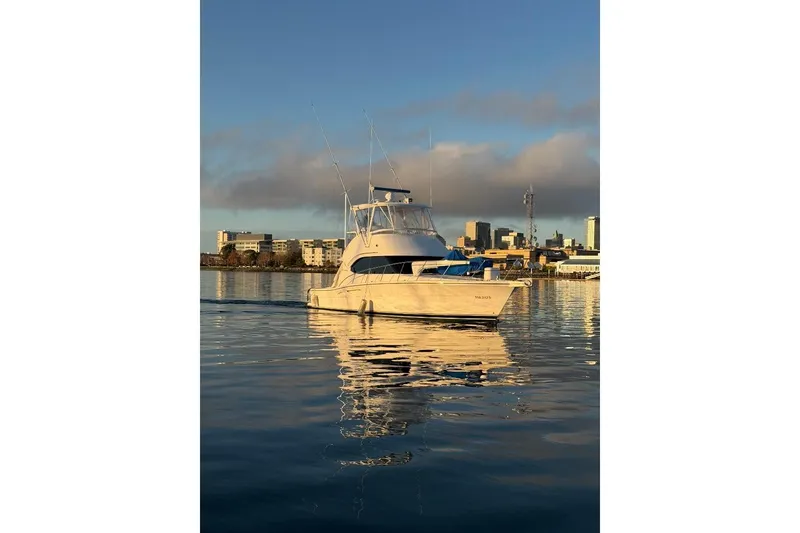 Slide: The Image of 2004 Riviera Convertible yacht on calm water with city skyline backdrop. - 1