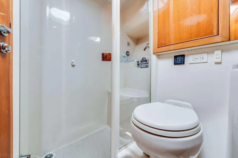 Slide: The Image of 2004 Riviera Convertible yacht bathroom with shower, toilet, and wooden cabinetry. - 11