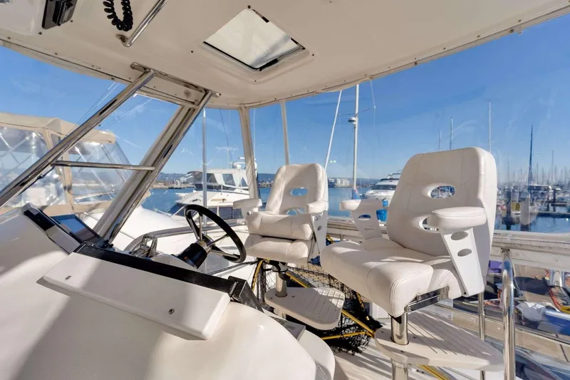 Slide: The Image of 2004 Riviera Convertible yacht helm with white captain chairs and marina view. - 19