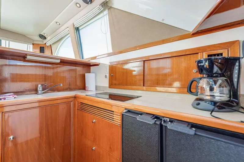 Slide: The Image of 2004 Riviera Convertible yacht kitchen with wooden cabinets and coffee maker. - 27