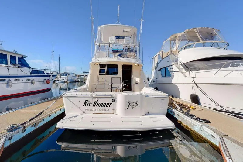 Slide: The Image of 2004 Riviera Convertible yacht docked at marina, rear view with clear blue sky. - 33
