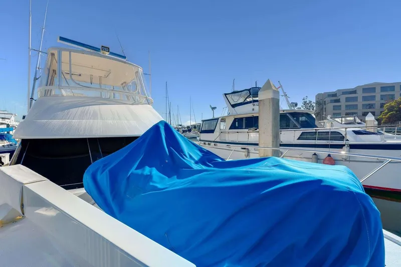 Slide: The Image of 2004 Riviera Convertible boat docked, covered with blue tarp, in a marina setting. - 35