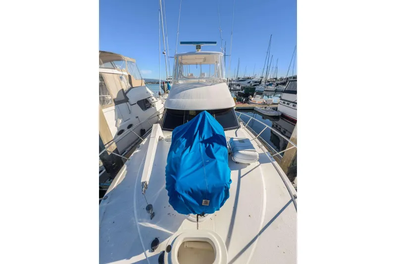 Slide: The Image of 2004 Riviera Convertible yacht docked at marina, blue cover on deck, clear sky. - 36