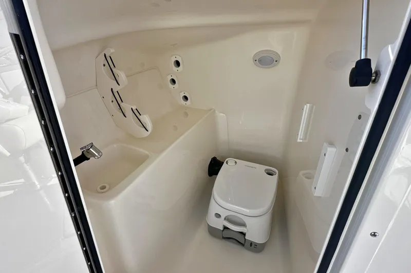 Slide: The Image of Interior of 2026 Key West 239 DFS boat featuring compact marine toilet. - 18