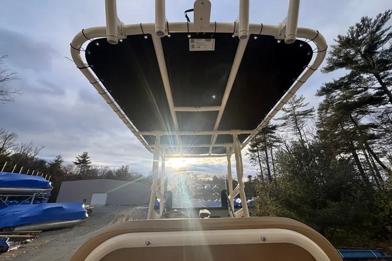 Slide: The Image of 2026 Bayliner Trophy T20CC boat with sun canopy, surrounded by trees and storage area. - 10