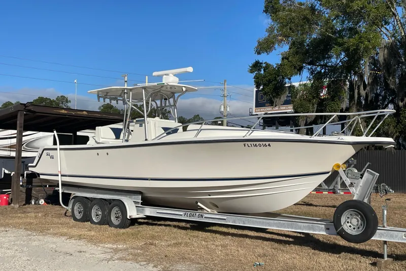 The Image of 2004 SeaVee 320i Cuddy boat on trailer, parked outdoors under clear blue sky. - 0