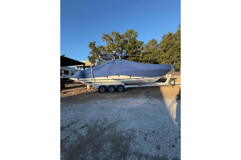 Slide: The Image of 2004 SeaVee 310i Cuddy boat covered on trailer, parked outdoors. - 26