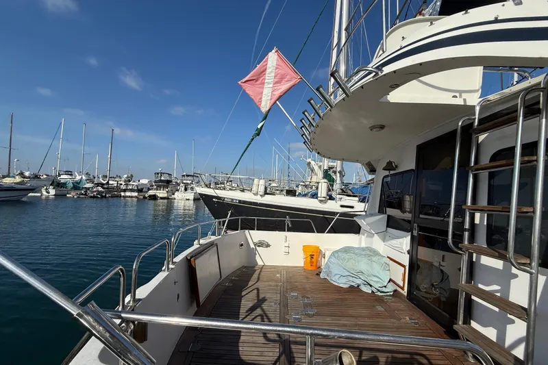 Slide: The Image of 1990 Mikelson 42 yacht docked at marina, featuring spacious deck and clear blue sky. - 12
