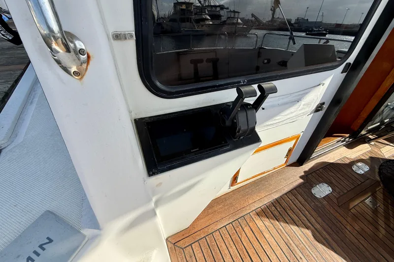 Slide: The Image of 1990 Mikelson 42 boat cockpit with control panel and wooden deck. - 14