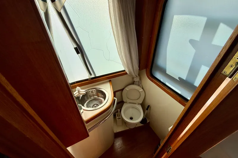Slide: The Image of 1990 Mikelson 42 yacht bathroom with sink, toilet, and frosted window. - 21