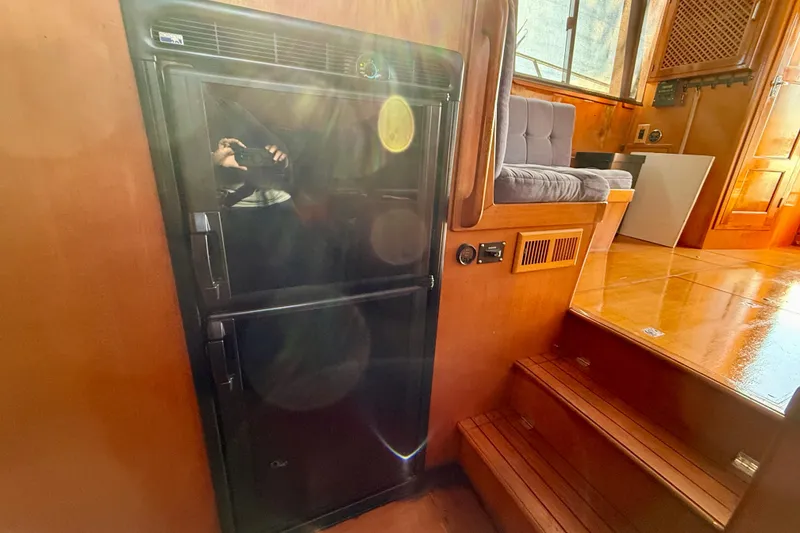 Slide: The Image of Interior of a 1990 Mikelson 42 yacht with a black refrigerator and wooden steps. - 23