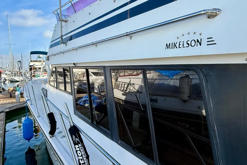 Slide: The Image of 1990 Mikelson 42 yacht docked at marina, showcasing sleek design and reflective windows. - 3