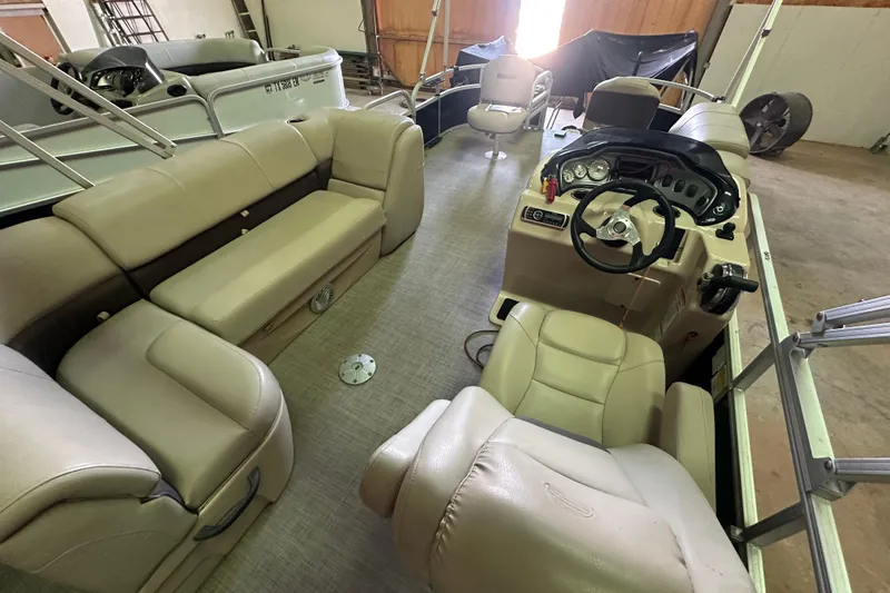 Slide: The Image of 2019 Sun Tracker Fishin' Barge 20 DLX interior with beige seating and steering console. - 10