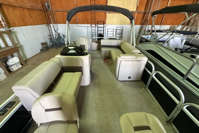 Slide: The Image of 2019 Sun Tracker Fishin' Barge 20 DLX pontoon boat with beige seating in a storage facility. - 21