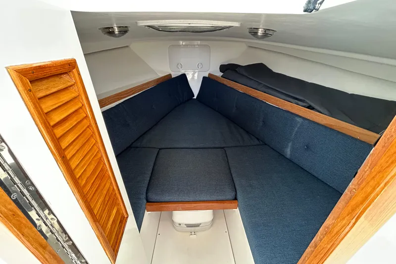 Slide: The Image of Cozy cabin interior of 2019 Limestone 26 boat with blue cushions and wooden accents. - 14