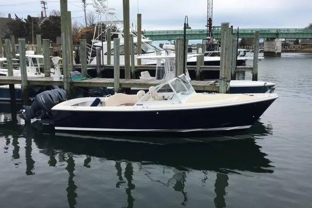 Slide: The Image of 2019 Limestone 26 boat docked in a marina, featuring a sleek design and outboard motor. - 4