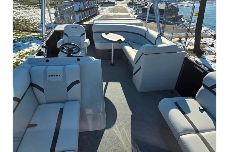 Slide: The Image of 2023 Crest Classic LX 200 pontoon boat interior with plush seating and steering console. - 11