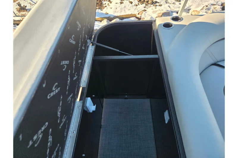 Slide: The Image of 2023 Crest Classic LX 200 boat interior storage compartment with cushioned seating and cup holders. - 18