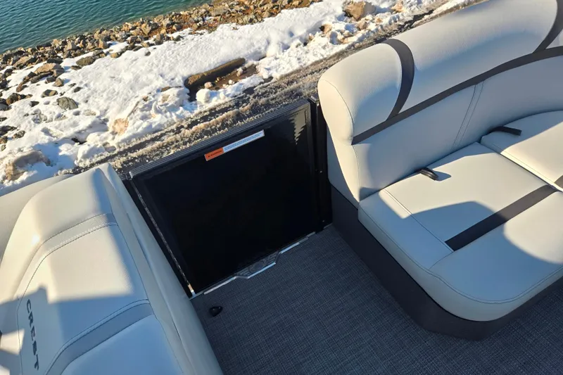 Slide: The Image of 2023 Crest Classic LX 200 boat interior with cushioned seating near snowy shoreline. - 23