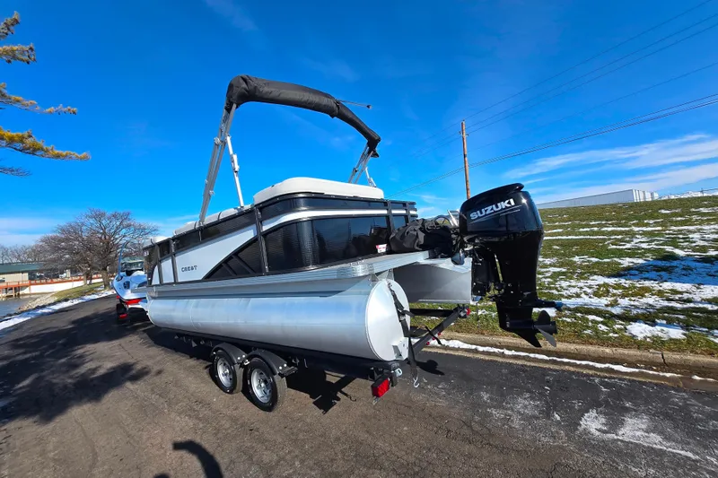 Slide: The Image of 2023 Crest Classic LX 200 pontoon boat with Suzuki motor on trailer, sunny day. - 3