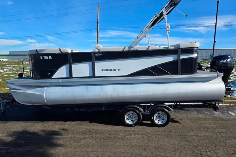 Slide: The Image of 2023 Crest Classic LX 200 pontoon boat on trailer, parked outdoors. - 4