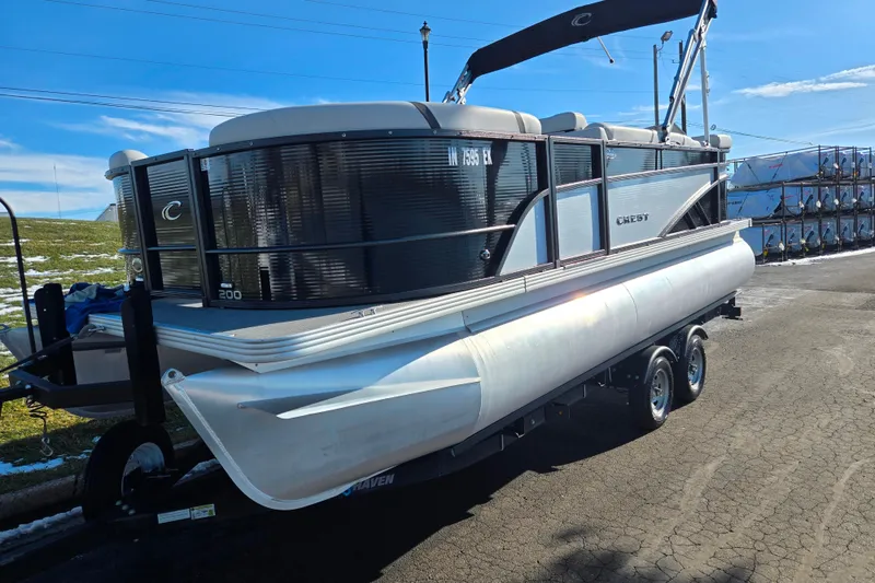 Slide: The Image of 2023 Crest Classic LX 200 pontoon boat on trailer, parked outdoors. - 5