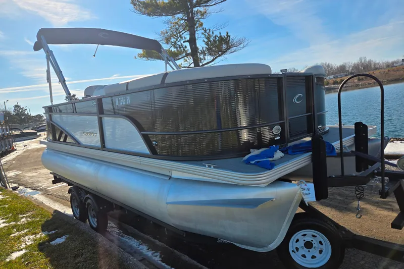Slide: The Image of 2023 Crest Classic LX 200 pontoon boat on trailer by a lake. - 8
