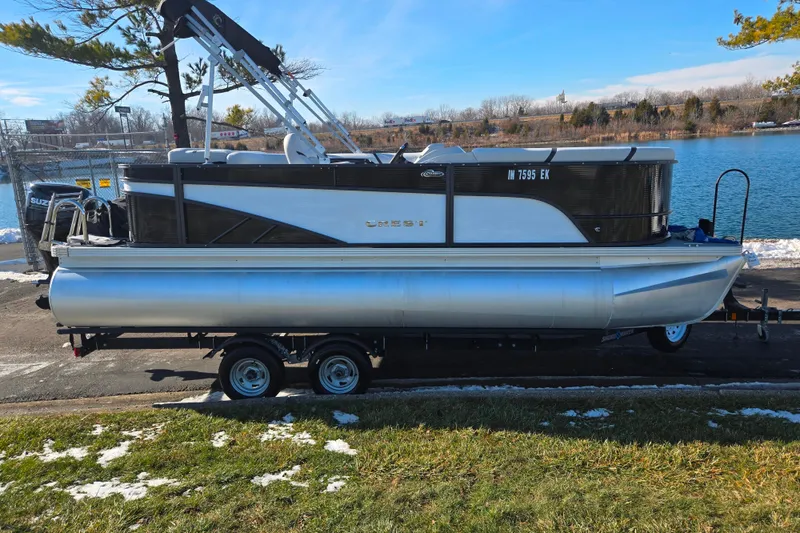 Slide: The Image of 2023 Crest Classic LX 200 pontoon boat on trailer by a lake. - 9