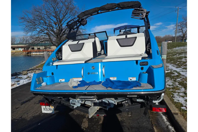 Slide: The Image of 2023 Yamaha Boats 222XD in blue, docked near a snowy lakeside. - 2