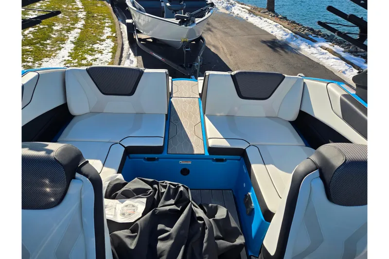 Slide: The Image of 2023 Yamaha Boats 222XD interior with white seating and blue accents by the water. - 25