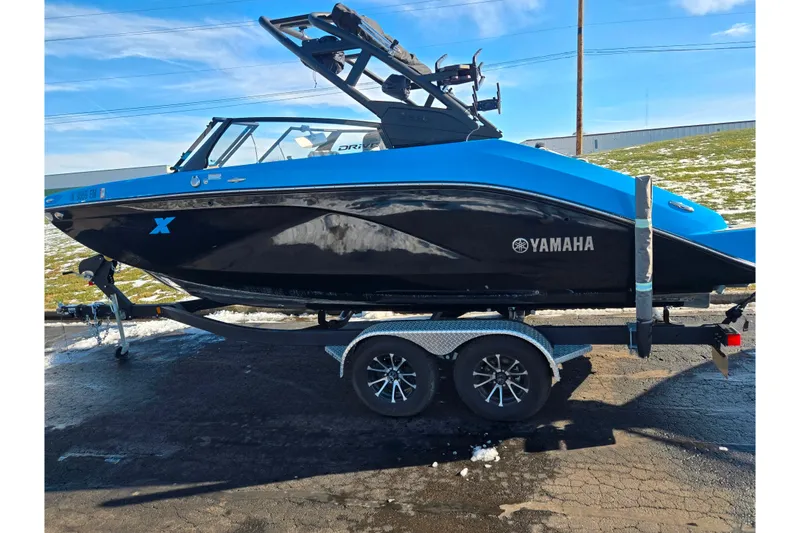 Slide: The Image of 2023 Yamaha Boats 222XD in blue and black on a trailer, parked outdoors. - 4