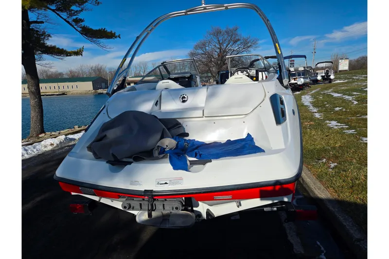 Slide: The Image of 2011 Sea-Doo 180 Challenger SE boat parked by a lake on a sunny day. - 2