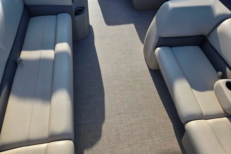 Slide: The Image of 2025 Sun Tracker Party Barge 18 DLX interior with beige seating and cup holders. - 10