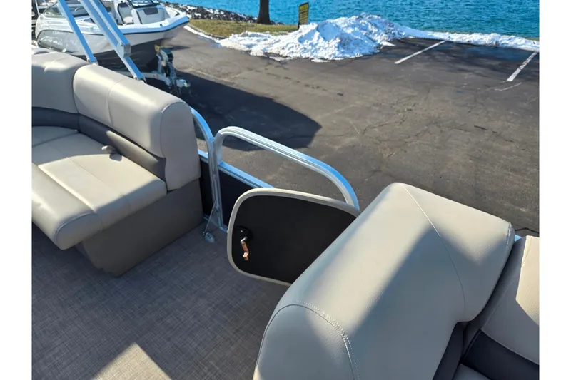 Slide: The Image of 2025 Sun Tracker Party Barge 18 DLX interior with beige seating near a snowy lakeside. - 12